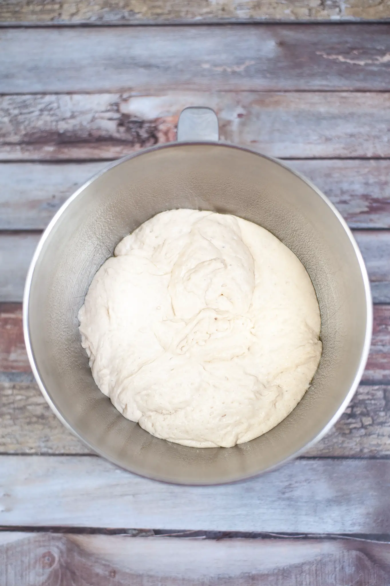 Uncooked pizza dough in a mixing bowl.