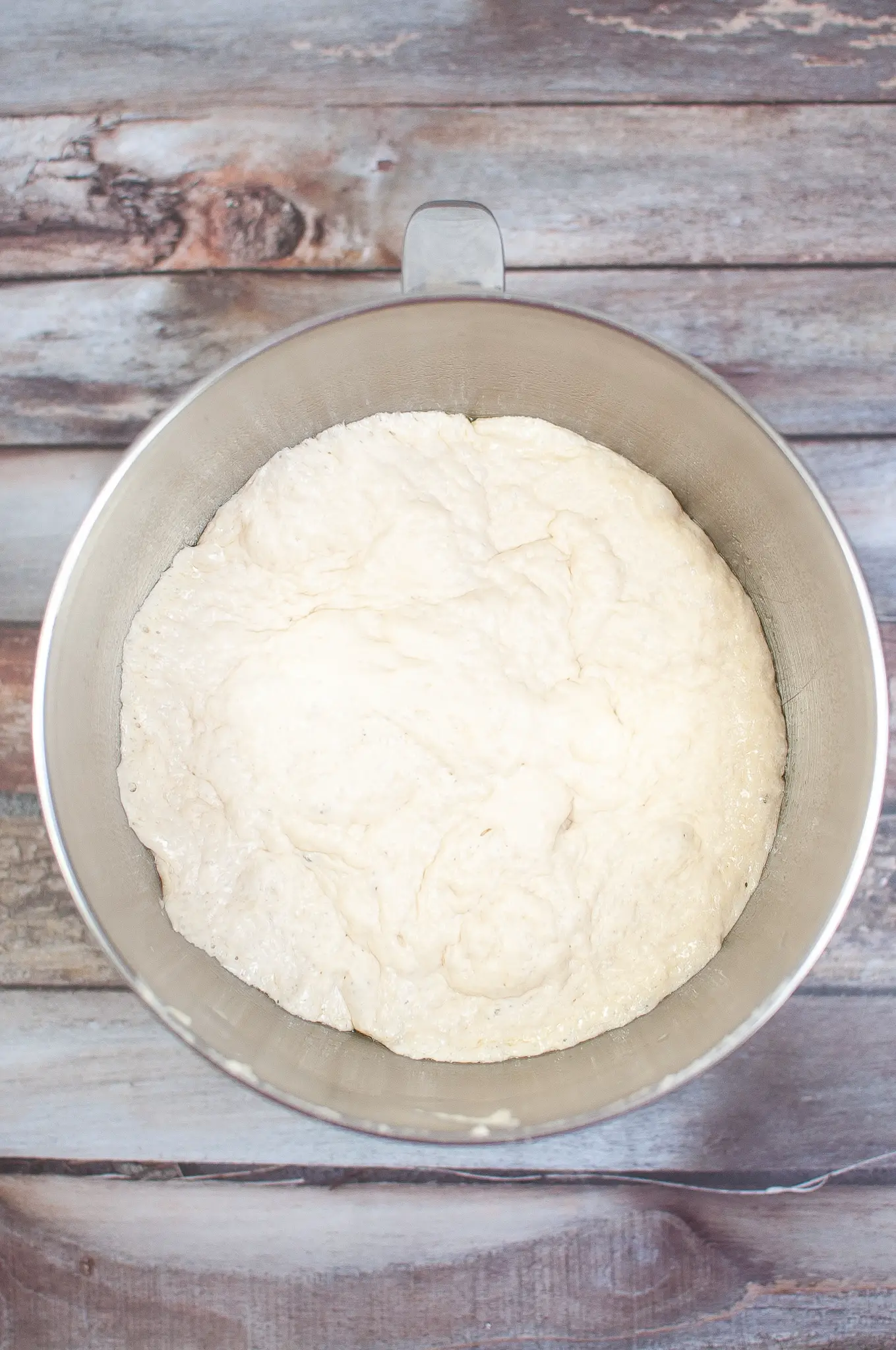 Uncooked proofed pizza dough in a mixing bowl.