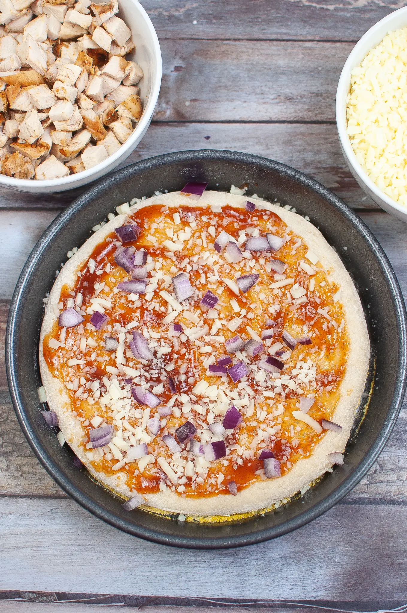 Pizza dough with bbq sauce, cheese and onion.