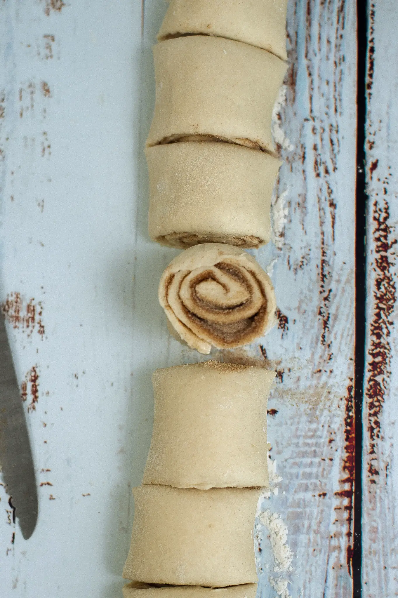 Cinnamon roll dough being cut into individual rolls.
