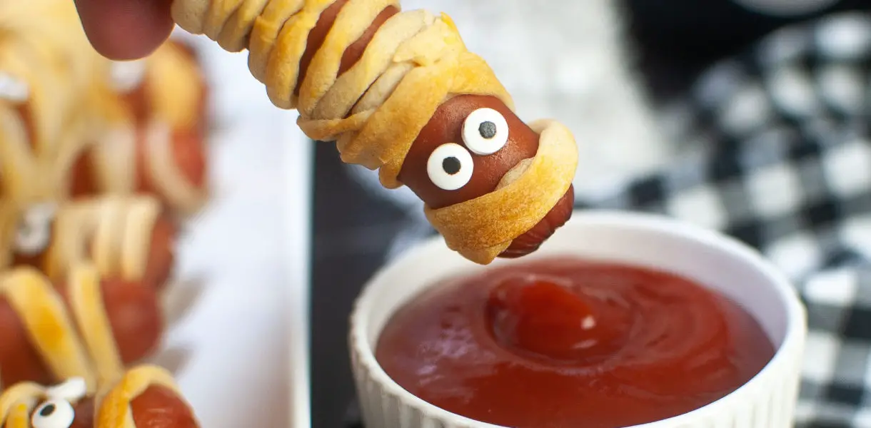 Mummy dog being dipped in ketchup