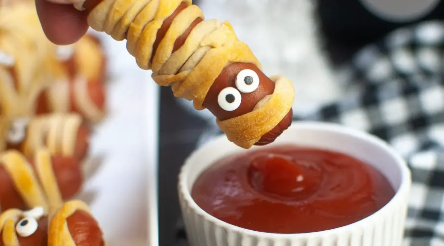 Mummy dog being dipped in ketchup